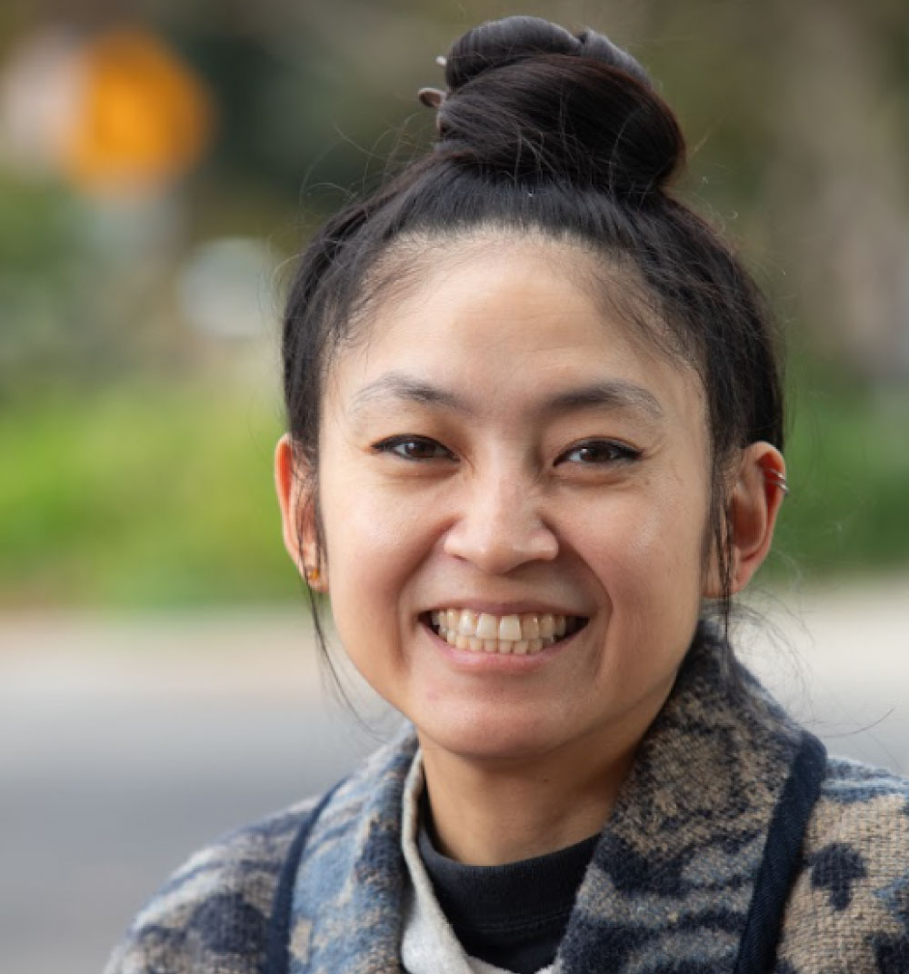 A woman with a bun smiles warmly, showcasing her joyful expression and friendly demeanor.