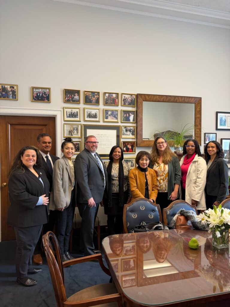 A larger group meeting photo around a conference table in an office